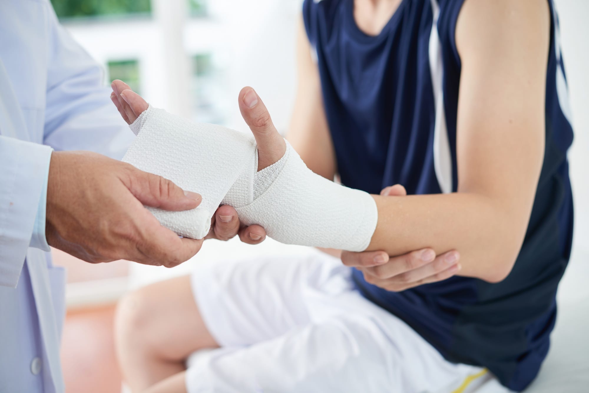 Unrecognizable doctor dressing injured hand of patient